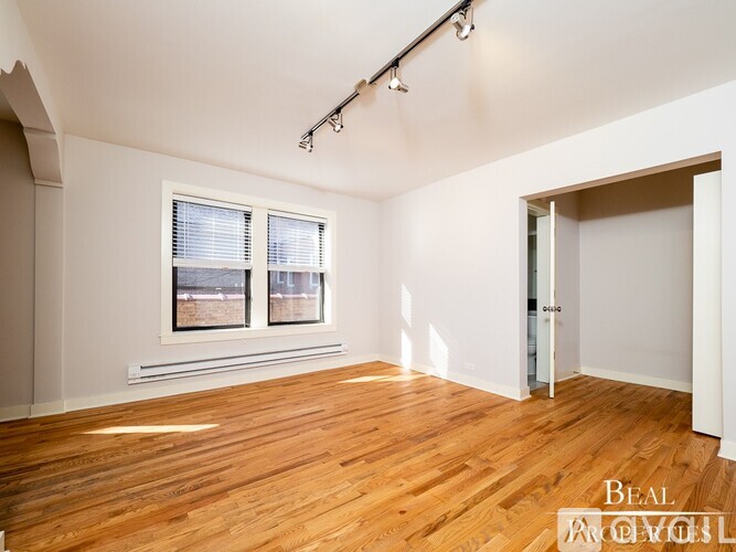 A room with wooden floors and a window with blinds.
