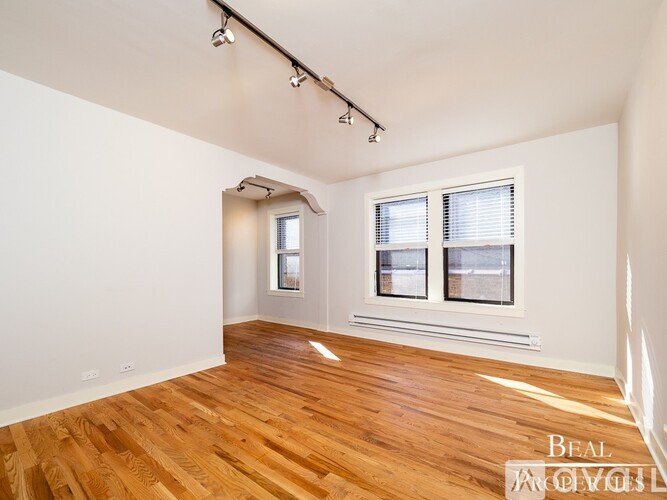 A room with wooden flooring and a window with blinds.