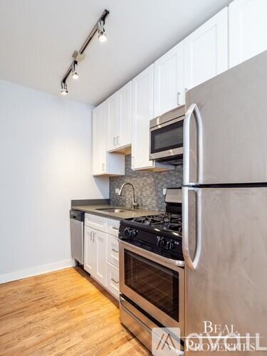 A modern kitchen with a stainless steel refrigerator, oven, and microwave.