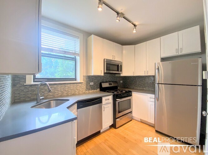 A modern kitchen with stainless steel appliances and wooden flooring.