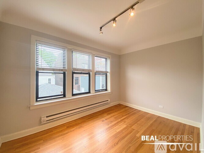 A room with wooden floors and three windows.