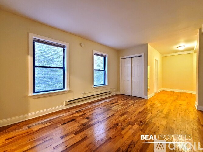 A room with wooden floors and two windows.