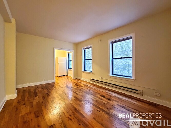 A room with wooden floors and two windows.