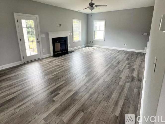 A spacious room with wood flooring and a fireplace.