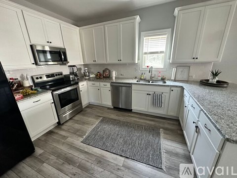 A kitchen with white cabinets and a black refrigerator.