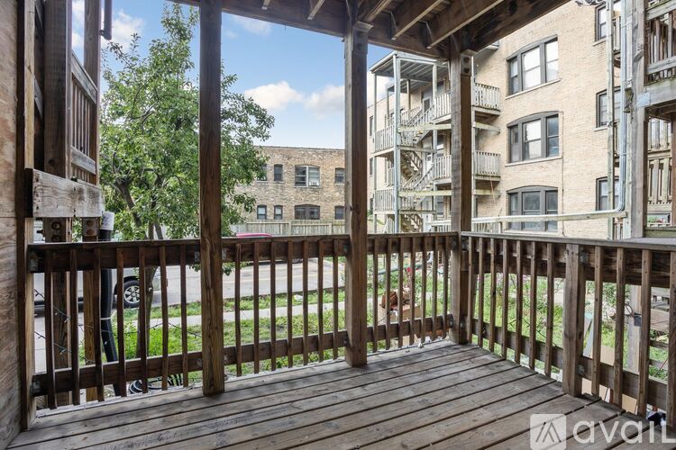 A wooden deck with a view of a grassy area and apartment buildings.
