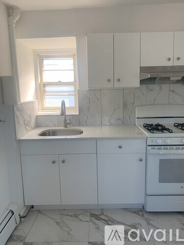 A kitchen with white cabinets and a marble countertop.