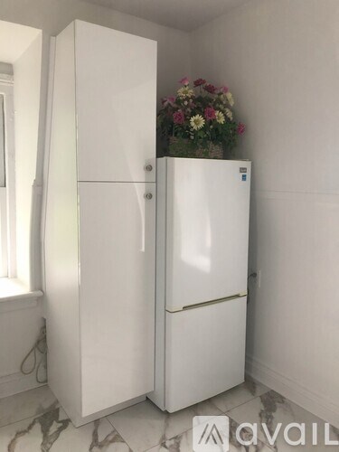 A white fridge with a flower pot on top.