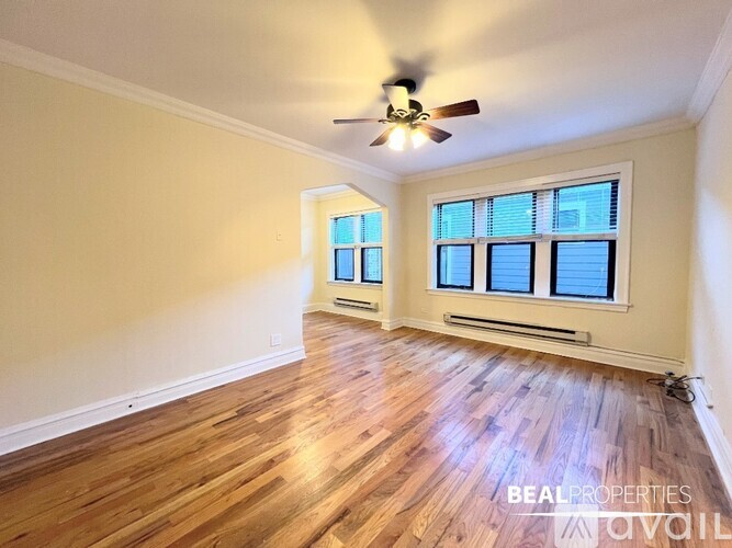 A spacious room with a ceiling fan and wooden flooring.