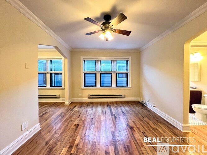 A spacious room with a ceiling fan and wooden flooring.
