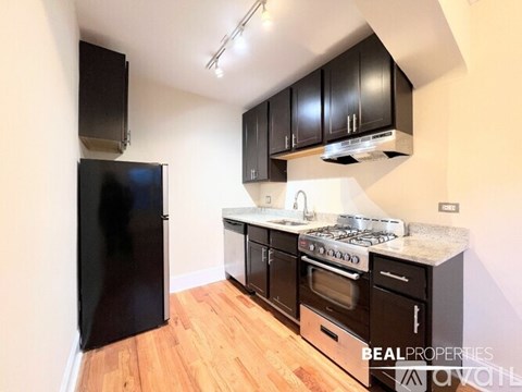 A kitchen with black cabinets and a white refrigerator.