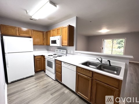 A kitchen with white appliances and wooden cabinets.