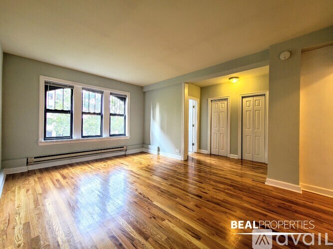 A room with wooden floors and a window with a view of trees.