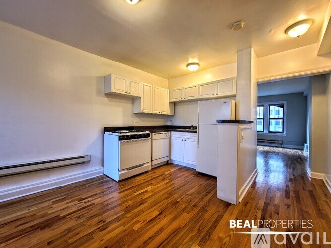 A kitchen with white appliances and wooden floors.