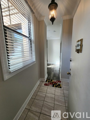 A hallway with a checkered floor mat and a light hanging from the ceiling.