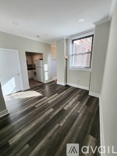 A room with wooden flooring and a window with blinds.
