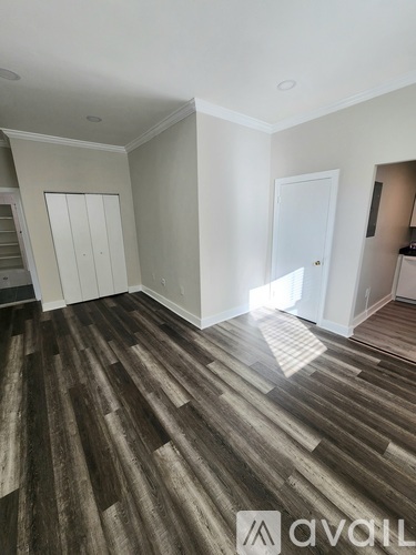 A room with wooden flooring and white walls.
