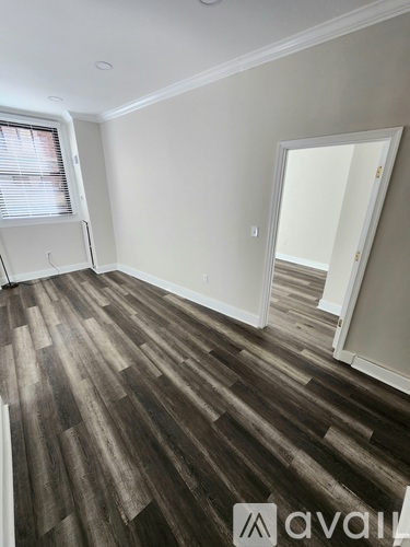 A room with wooden flooring and a white wall.