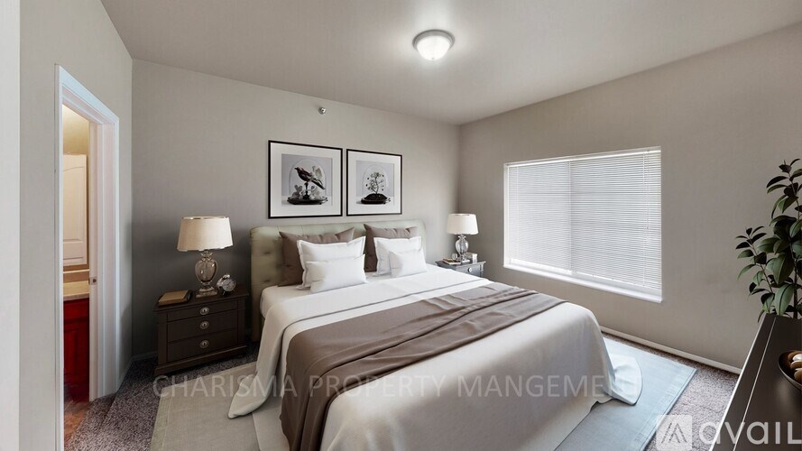 A bedroom with a bed, two lamps, and two pictures on the wall.