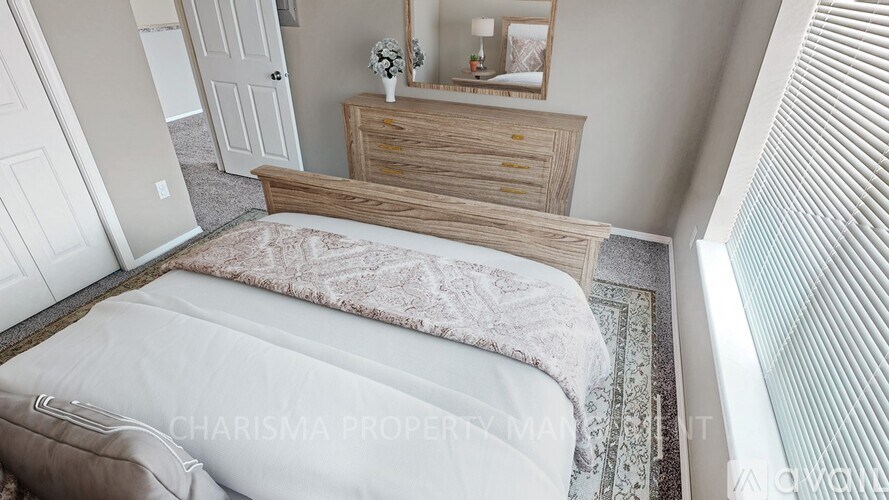 A bedroom with a bed, dresser, and mirror.