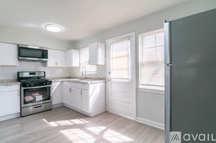 A kitchen with white cabinets and a grey fridge.