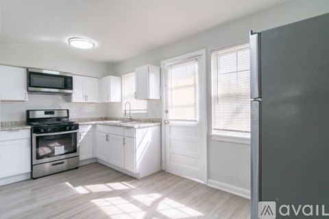 A kitchen with white cabinets and a grey fridge.