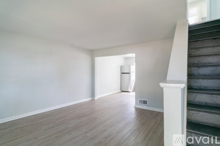 A room with wooden floors and a staircase on the right side.