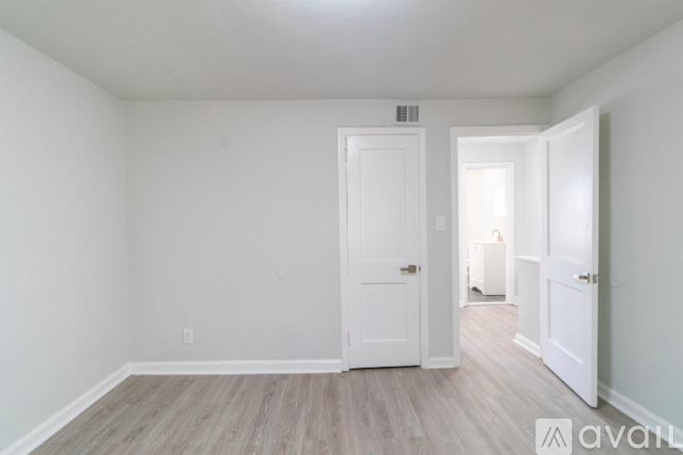 A room with a white door and a wooden floor.