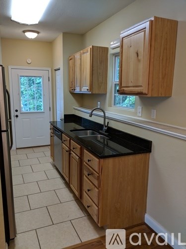 A kitchen with wooden cabinets and a black countertop.