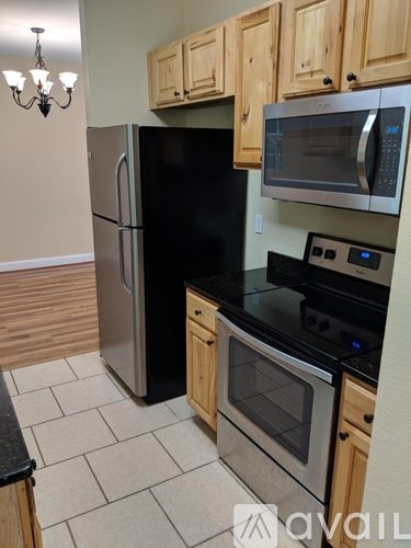 A kitchen with a black fridge, stove, and microwave.