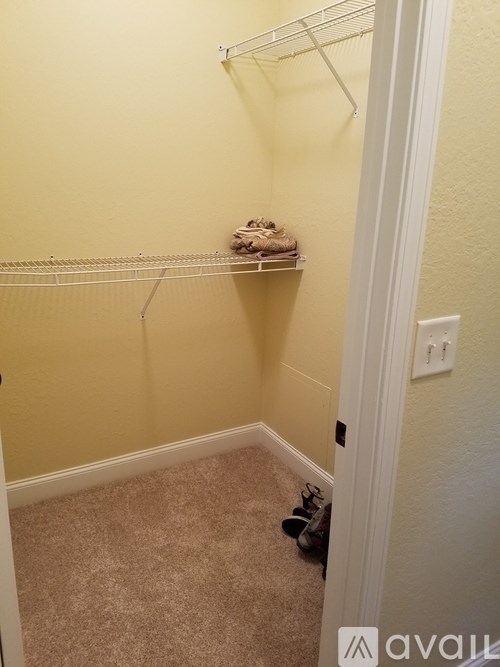 A small, empty room with a white door and a white shelf with clothes on it.