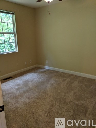 A room with a window and a carpeted floor.