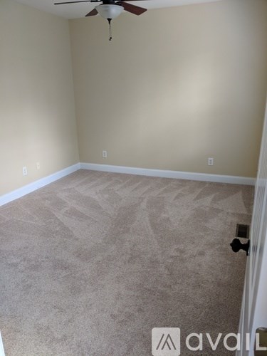 A room with a carpeted floor and a ceiling fan.
