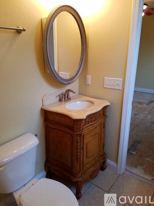 A bathroom with a toilet, sink, and mirror.