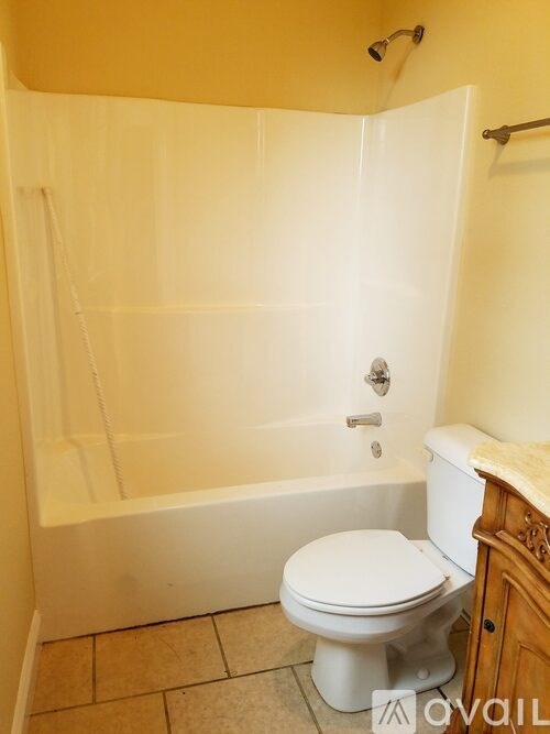 A white toilet sits in a bathroom next to a bathtub.