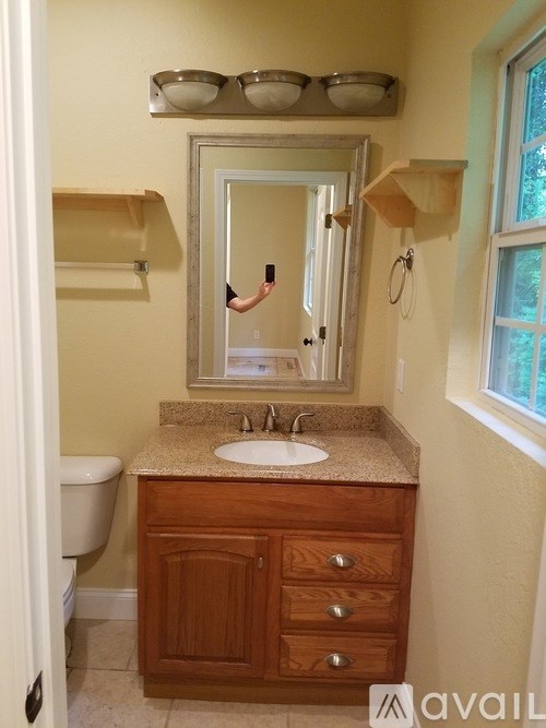 A bathroom with a sink, mirror, and wooden cabinet.