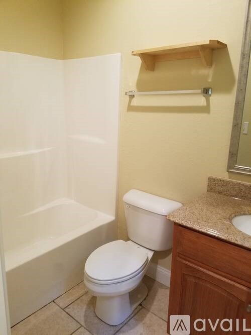 A white toilet sits in a bathroom next to a bathtub.