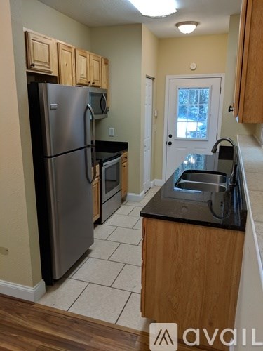 A kitchen with a black fridge and wooden cabinets.