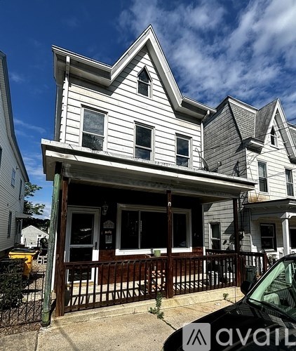 A white house with a black car parked in front.