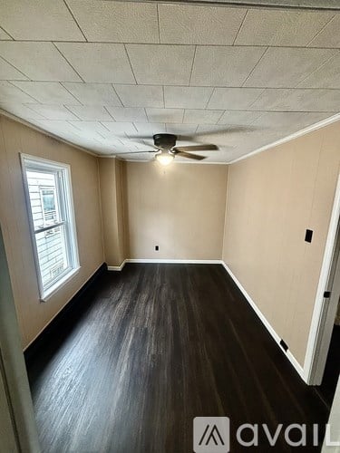 A room with a ceiling fan and wooden flooring.