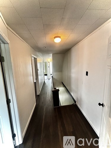 A long hallway with white walls and wood floors.