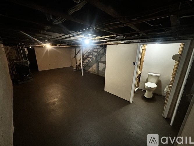 A room with a toilet and a staircase in the background.