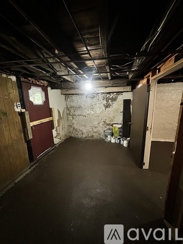 A room with a red door and a white wall with a clock on it.