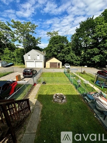 A backyard with a fence, a tree, and a house.