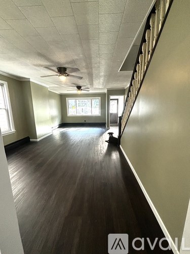 A long hallway with wood floors and a ceiling fan.