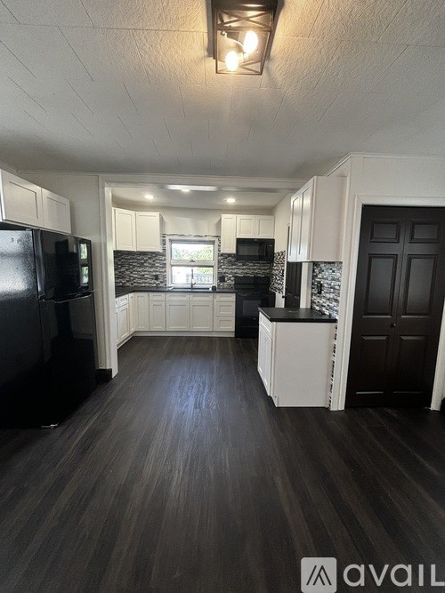 A kitchen with black appliances and white cabinets.