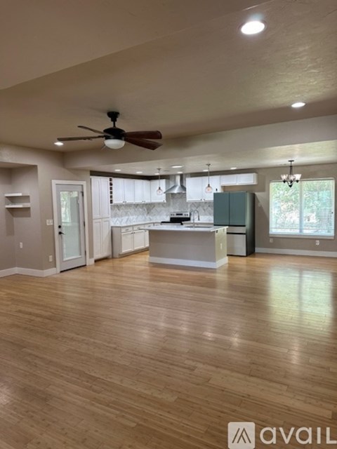 A spacious kitchen with a fan on the ceiling and wooden flooring.