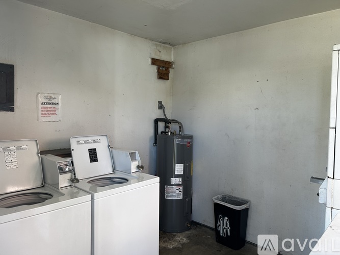 A room with a washing machine, a dryer, and a trash can.