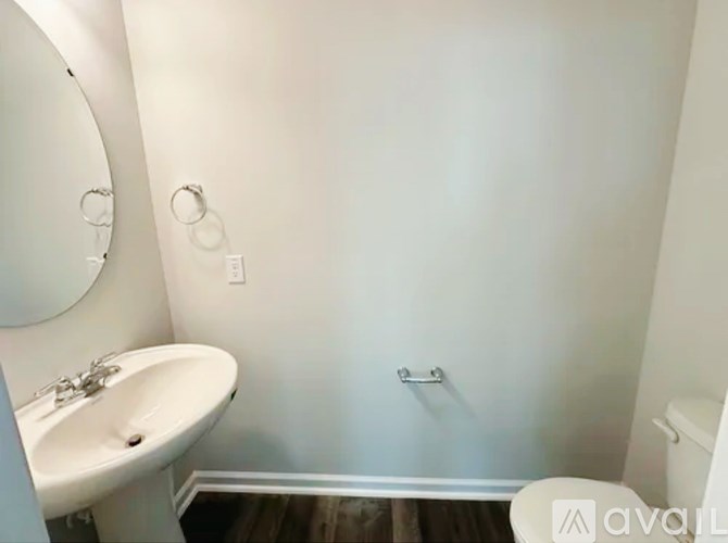 A white sink is in a small bathroom with a toilet and a towel rack.