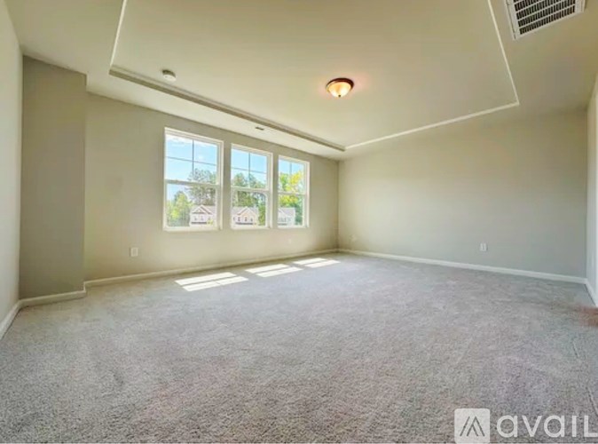 A room with a carpeted floor and a window showing a view of trees and a house.